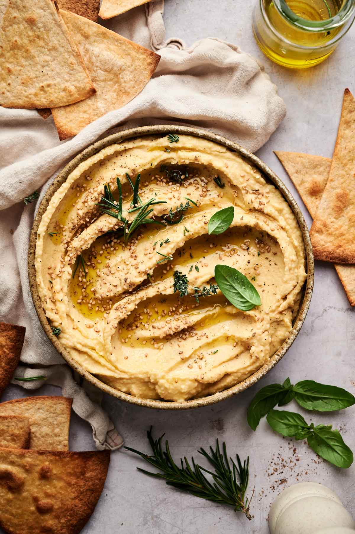 Hummus in a shallow bowl with fresh herbs on top.