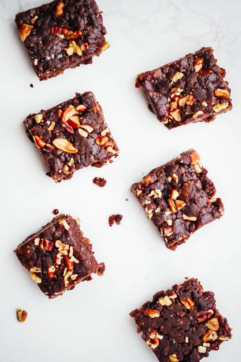 Six date bars topped with chopped pecans.