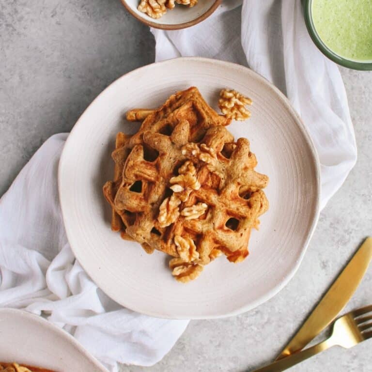 Applesauce waffles on a white plate with nuts on top.