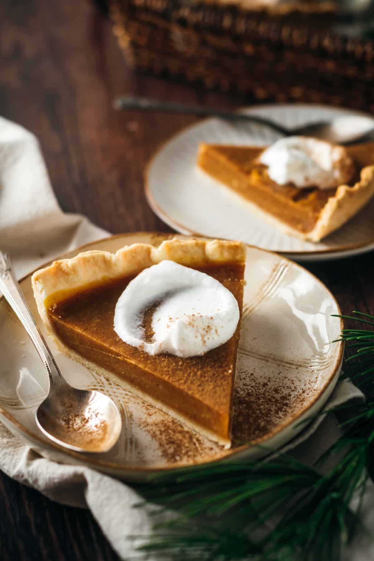 A slice of eggless pumpkin pie with a dollop of whipped cream on a plate with a spoon.