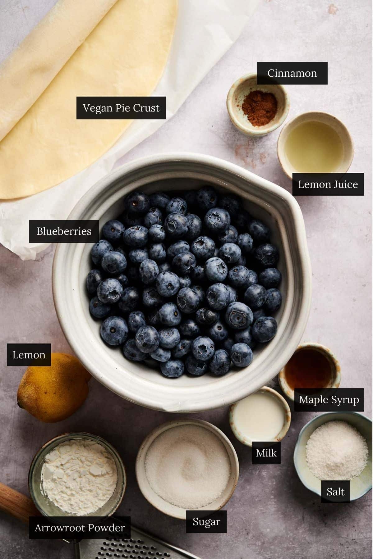 Ingredients in small to bowls for making blueberry pie with each ingredient labeled.