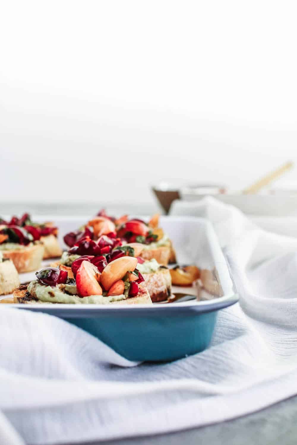 Cherry bruschetta with a balsamic glaze on a white enamel tray and white cloth napkins