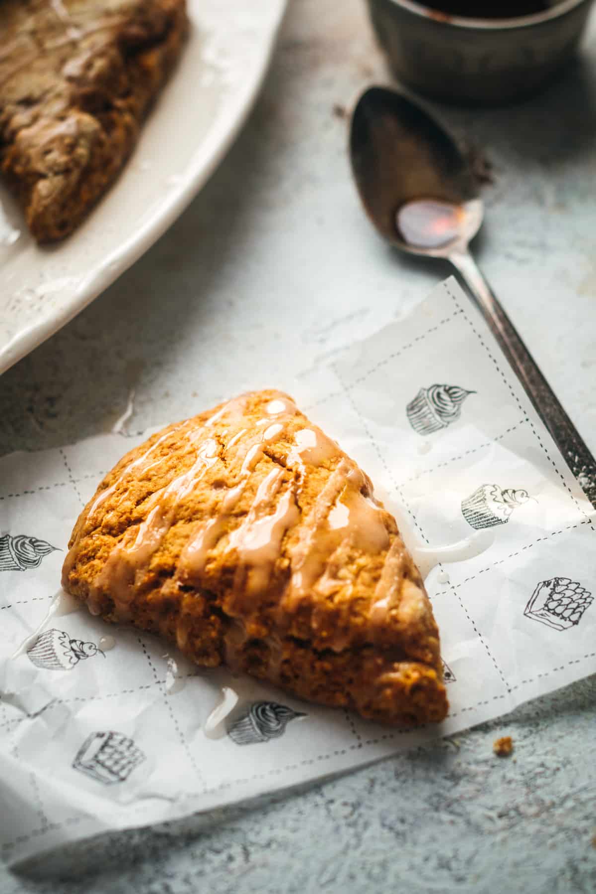 Close up of one vegan pumpkin scone on parchment paper.