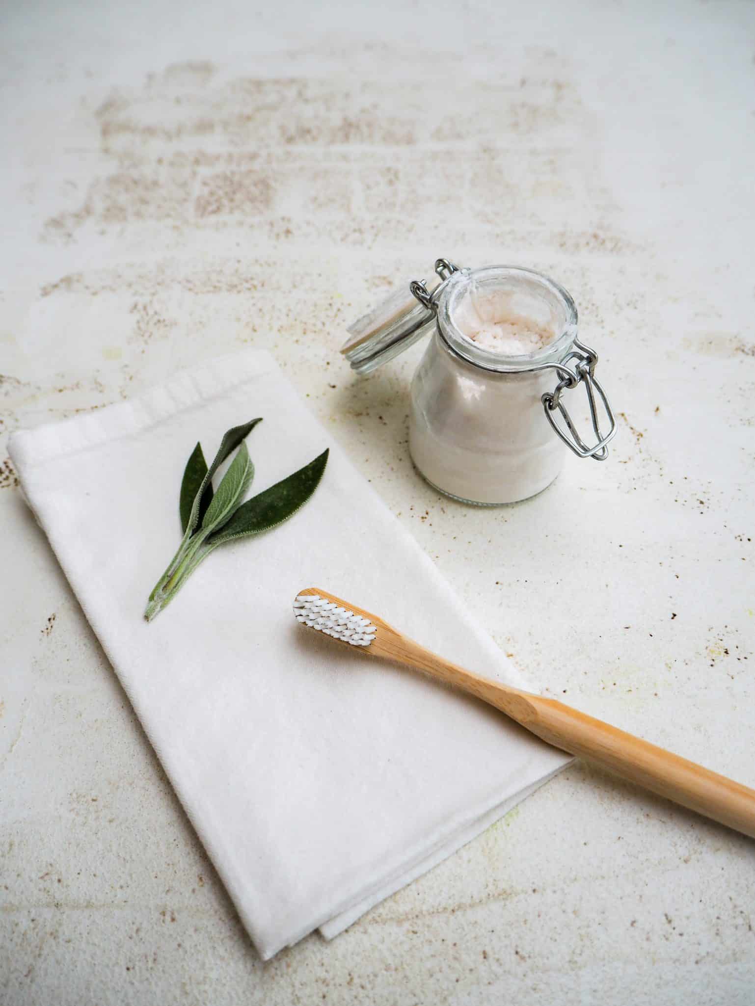 Bamboo toothbrush on a white napkin with zero-waste toothpaste powder.