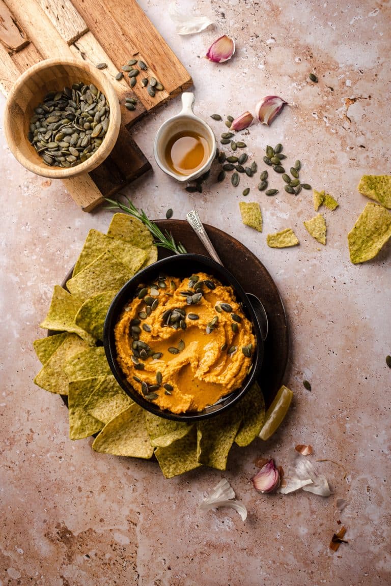 Bowl of pumpkin hummus with tortilla chips.
