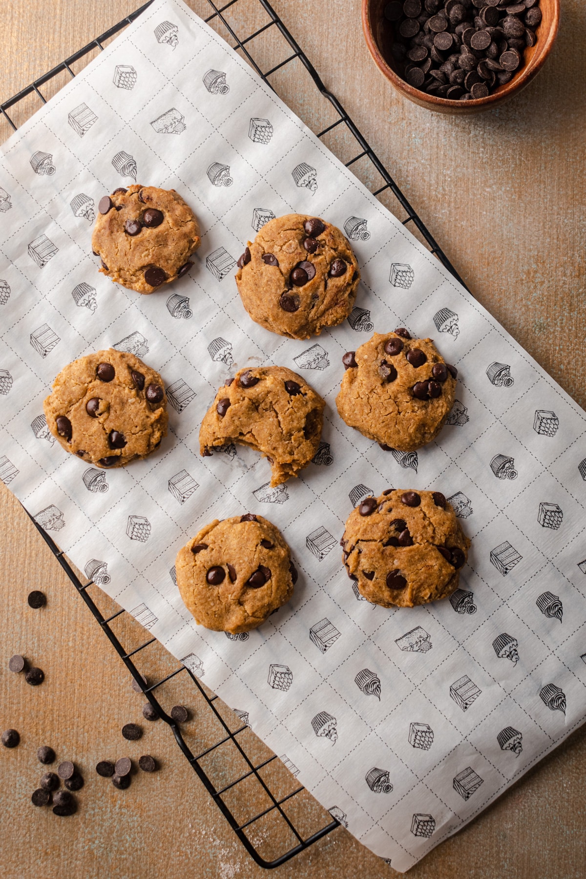 Pumpkin cookies on a cooling rack with parchment paper underneath.