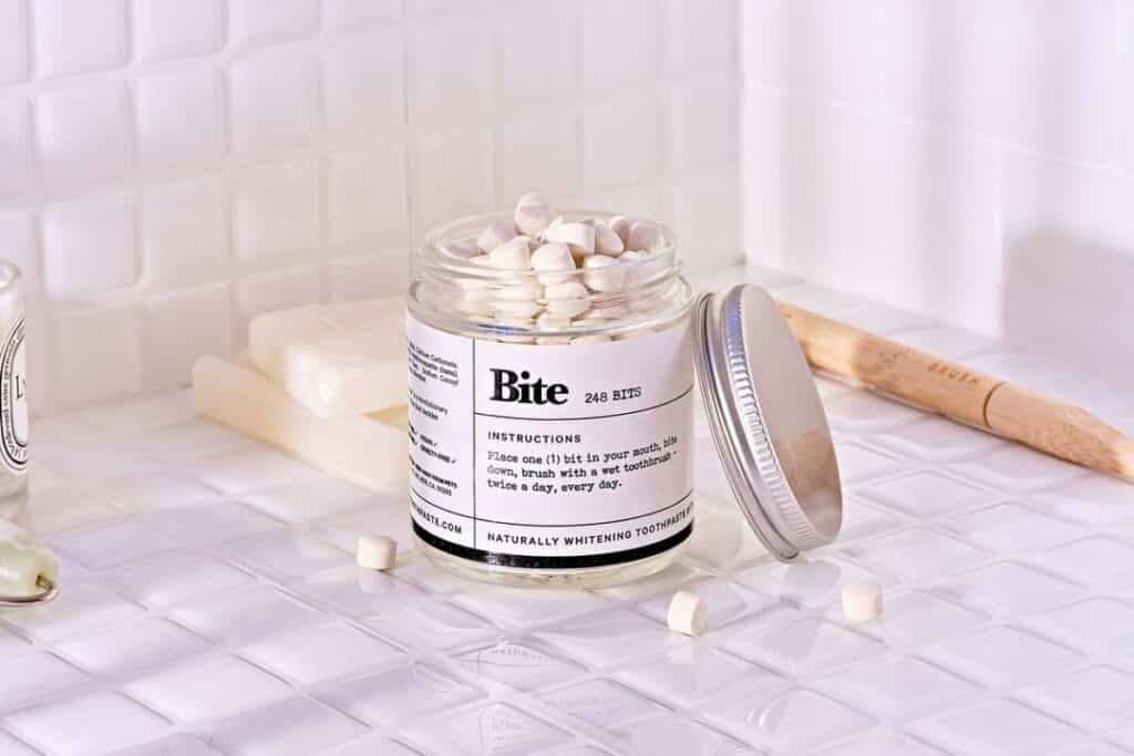 Glass jar with aluminum lid filled with toothpaste bits for a zero-waste smile.