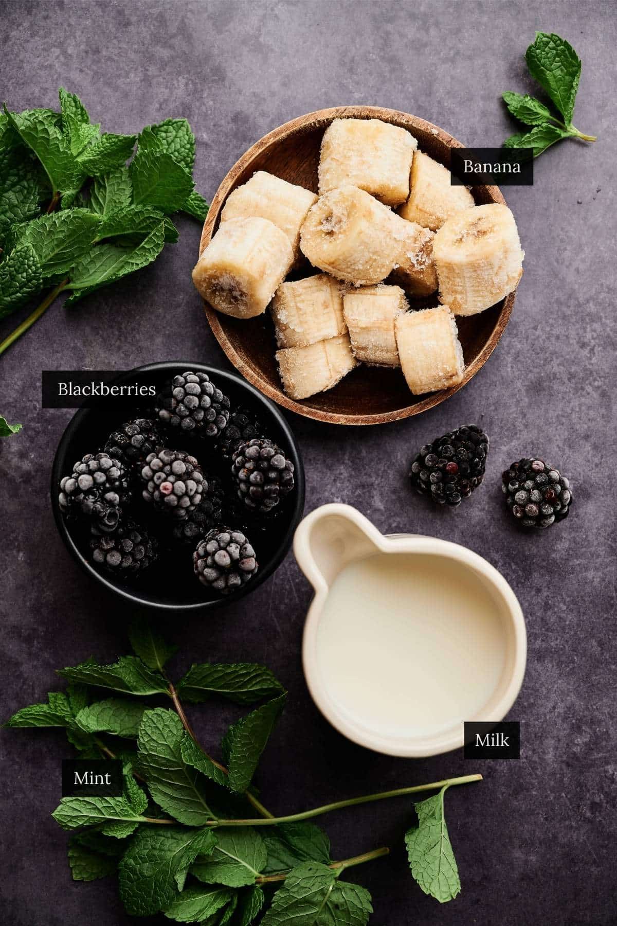 Ingredients for a blackberry smoothie on a charcoal counter.