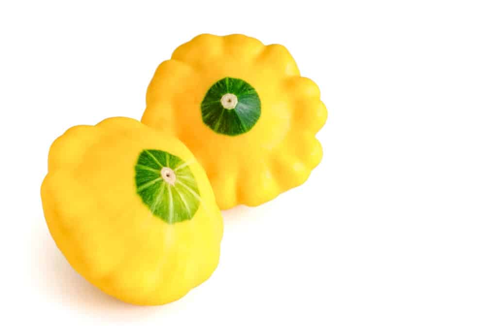 Two fresh patty pan squash with green stems.