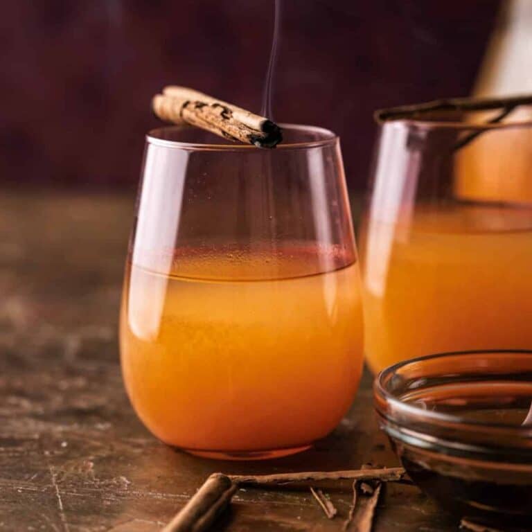 A glass cup of pumpkin lemonade with a cinnamon stick garnish.