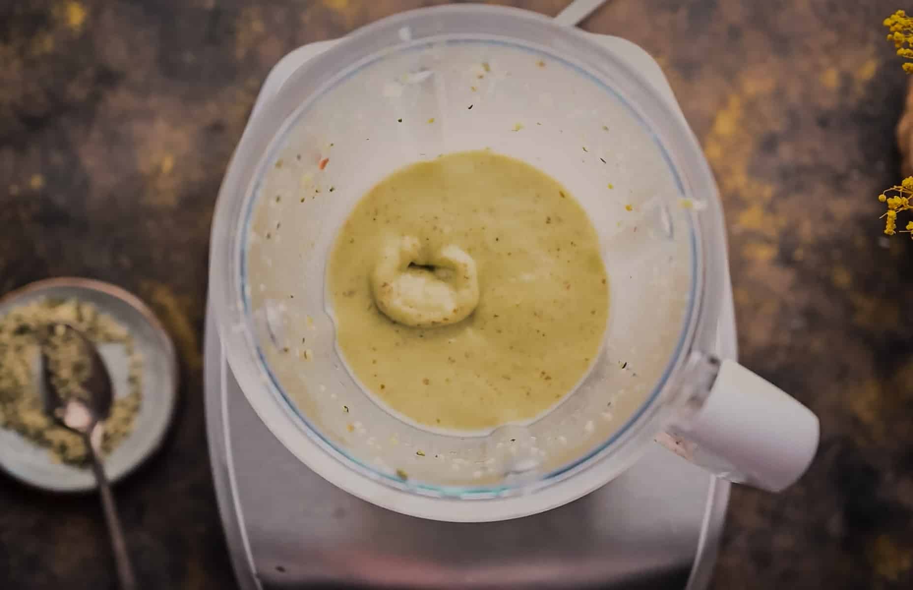 A blender filled with a thick green avocado smoothie sits on a counter.