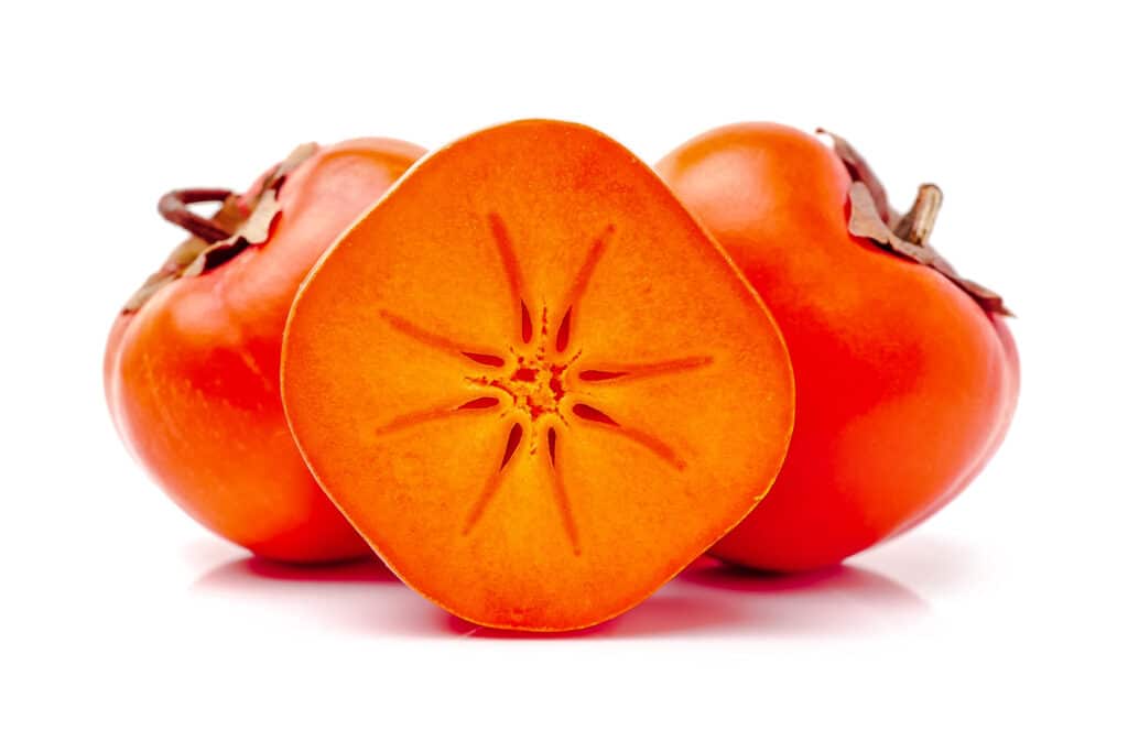 Two and a half Fuyu Persimmons showing the starburst pattern in the flesh.