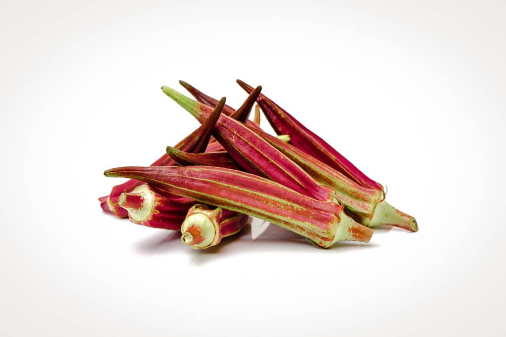 Pile of Jing Orange Okra on white surface.