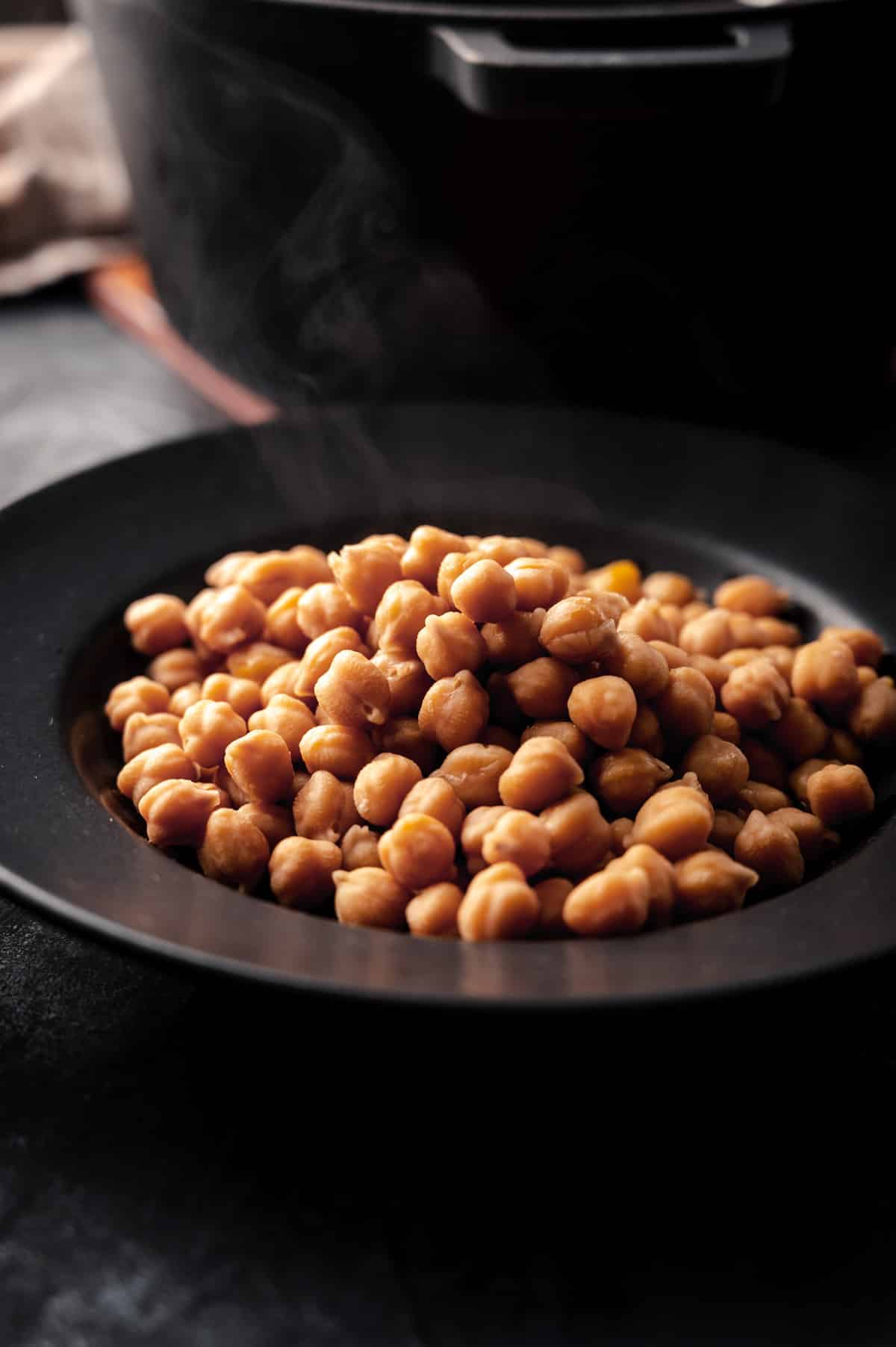 Cooked chickpeas in a shallow black bowl.