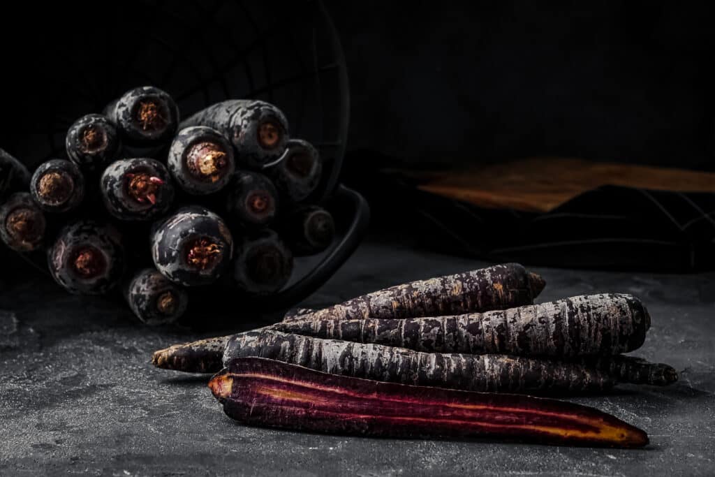 Black Nebula Carrots on a dark surface.