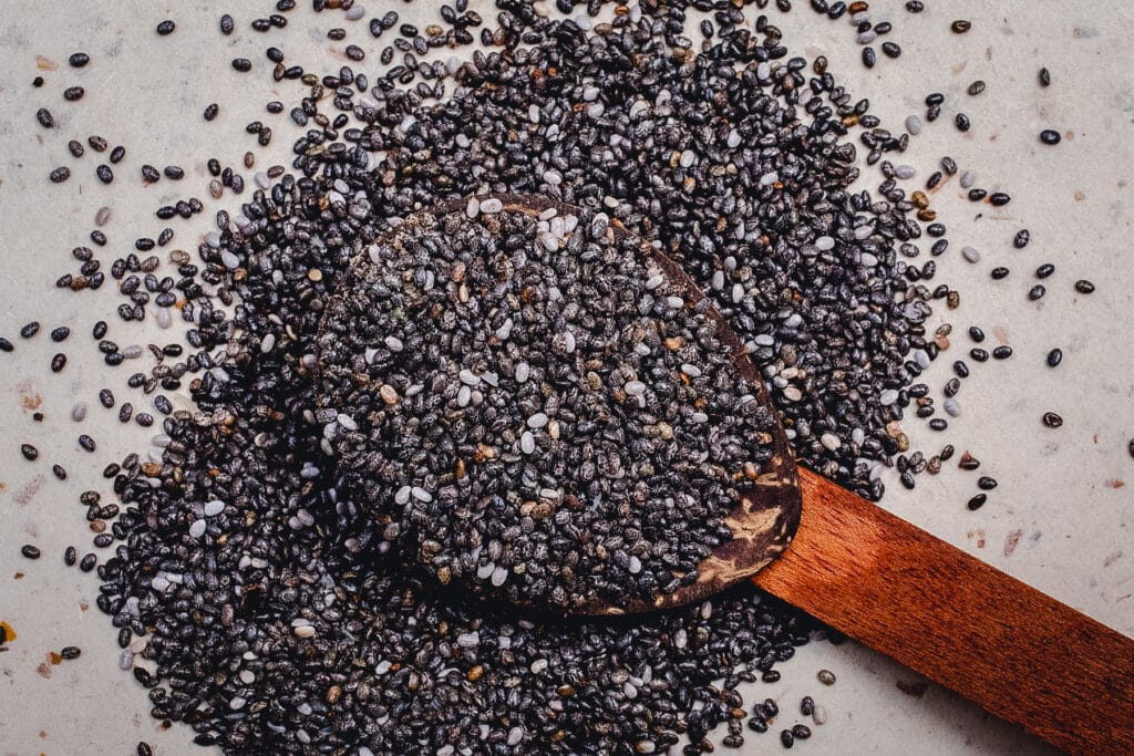Chia seeds in a wooden spoon overflowing onto the table.