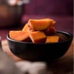 A black bowl filled with sliced pieces of cooked sweet potato on a wooden surface, showcasing the delicious results of learning how to boil sweet potatoes.