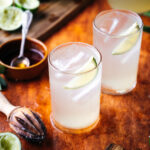 Two glasses of limeade and a juicer on the table.