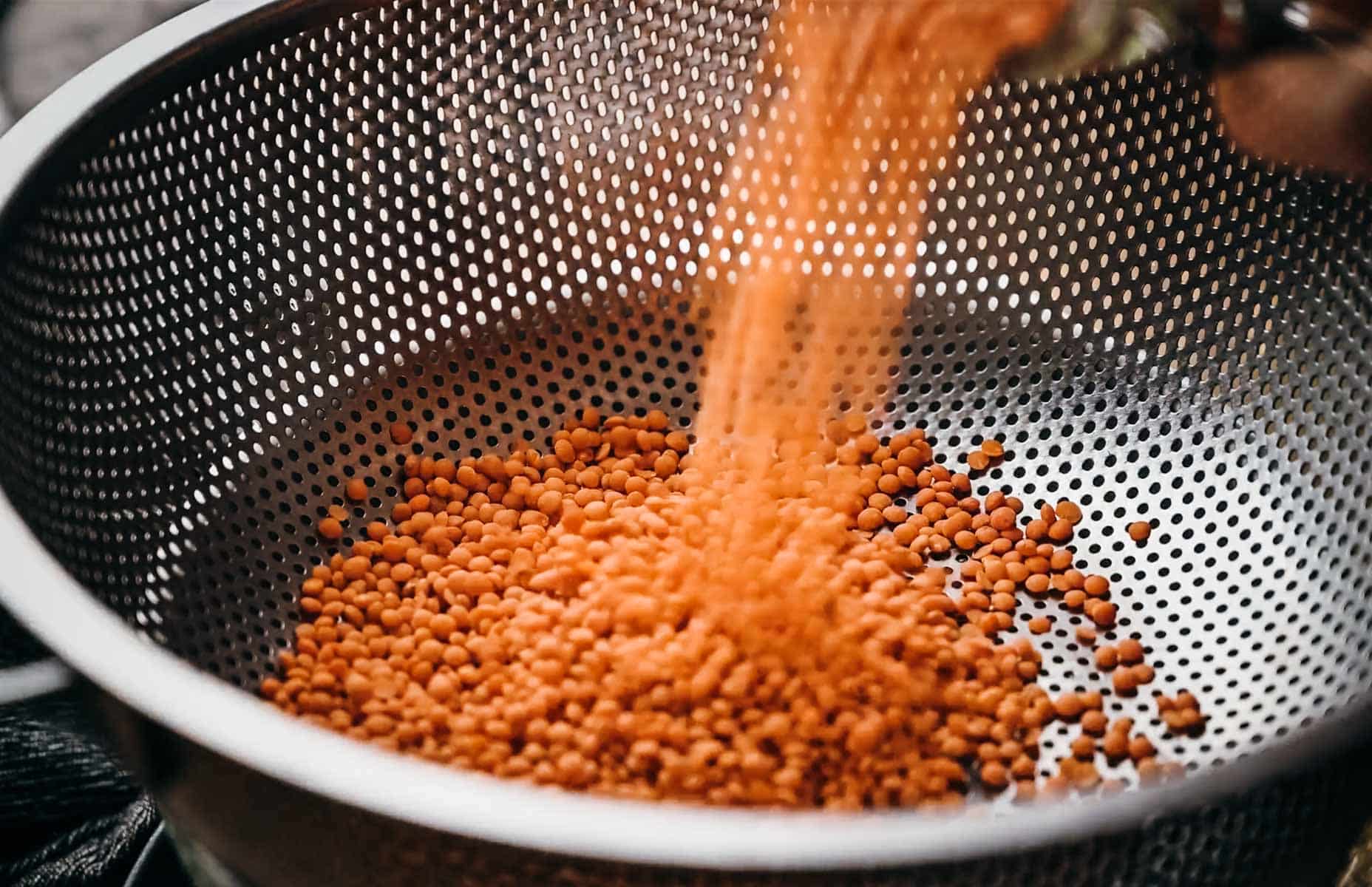 Lentils being poured into a silver colander.