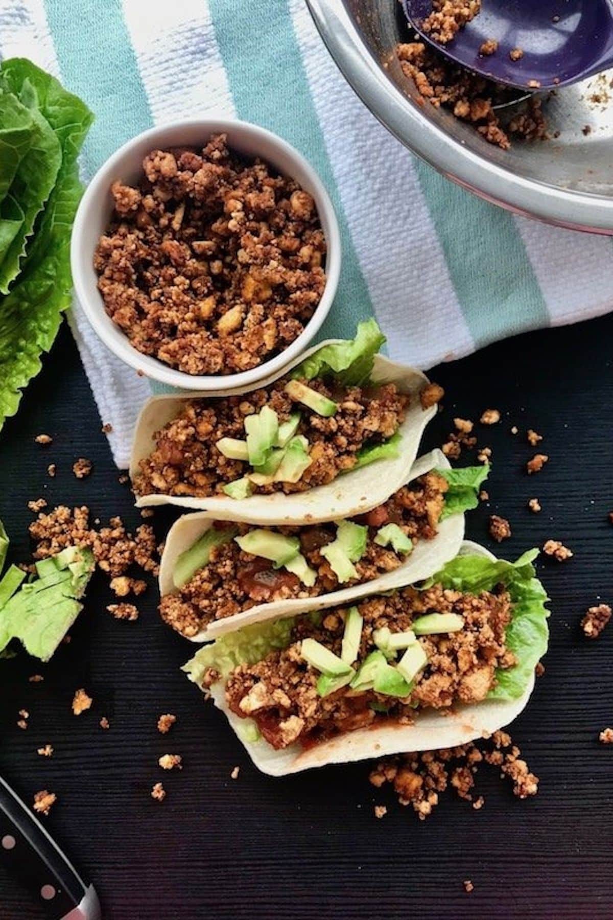 Lettuce wraps with vegan tofu and avocado on a table.