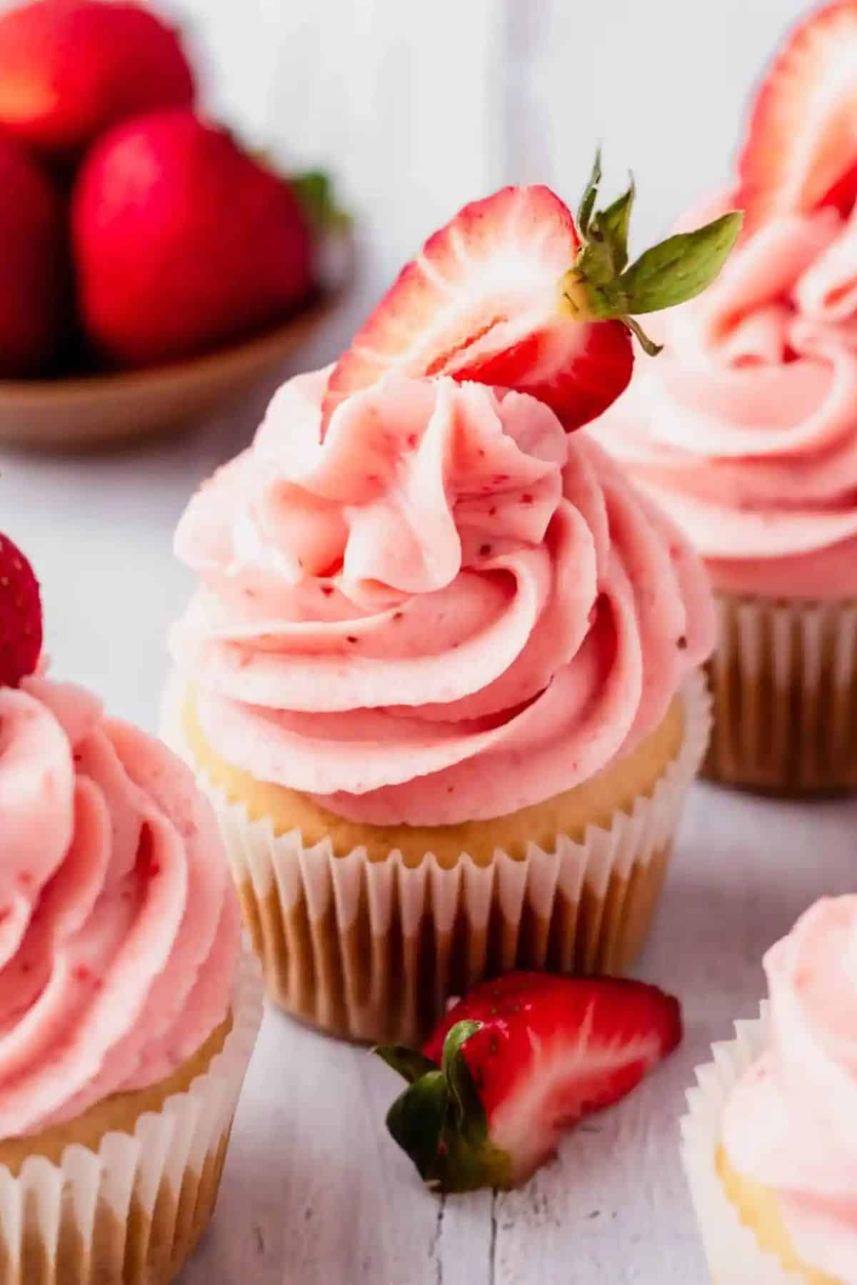 Vanilla cupcake with strawberry frosting with sliced strawberry on top.