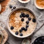 A bowl of creamy oatmeal topped with blueberries and peanut butter.