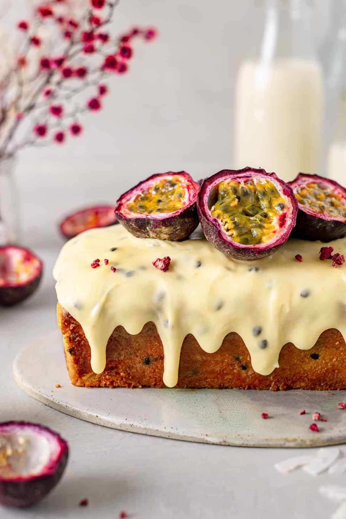 Passionfruit cake dripping in vegan frosting with fresh passionfruit on top.