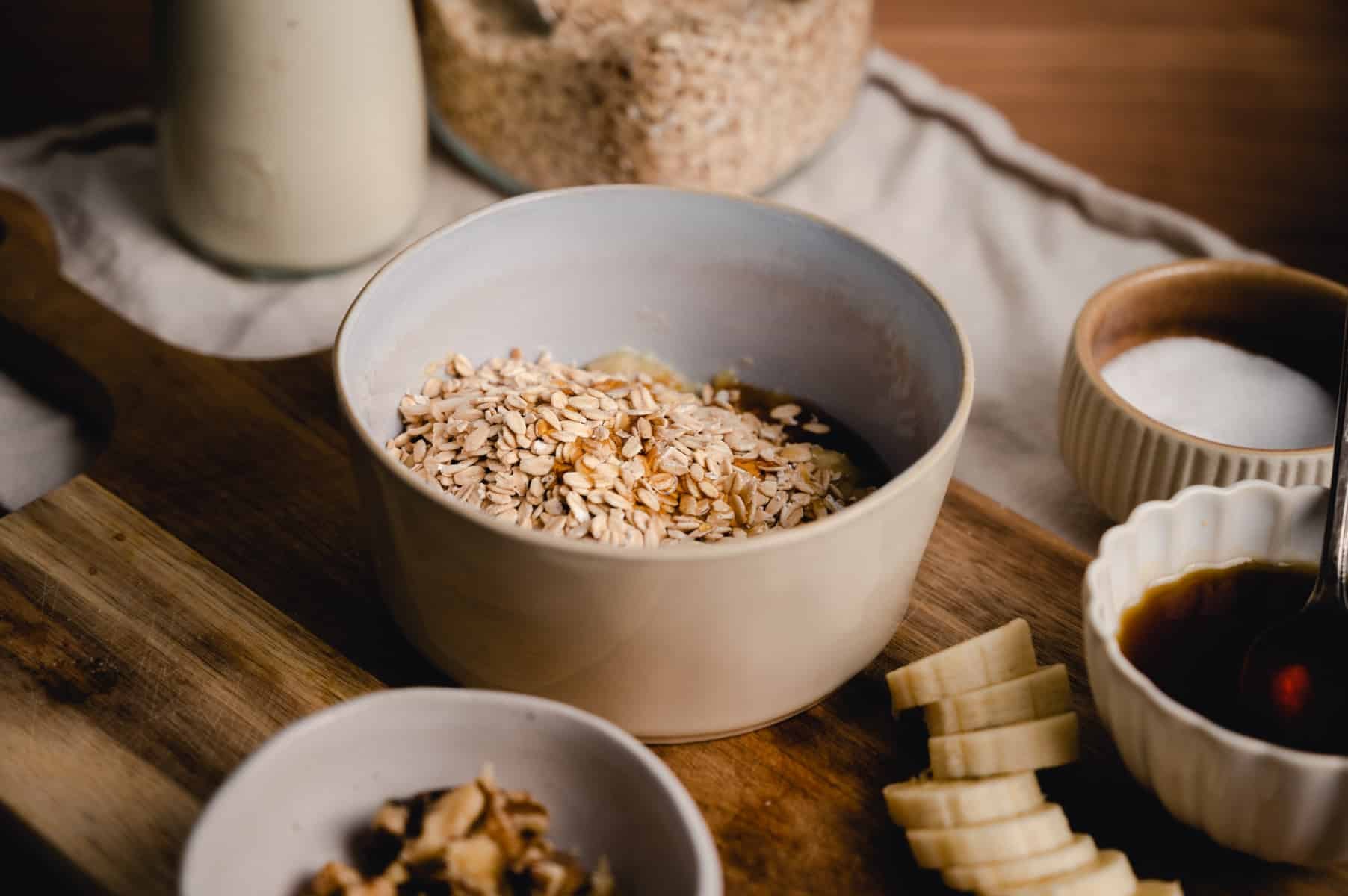 A white bowl filled with oats on a wooden board.