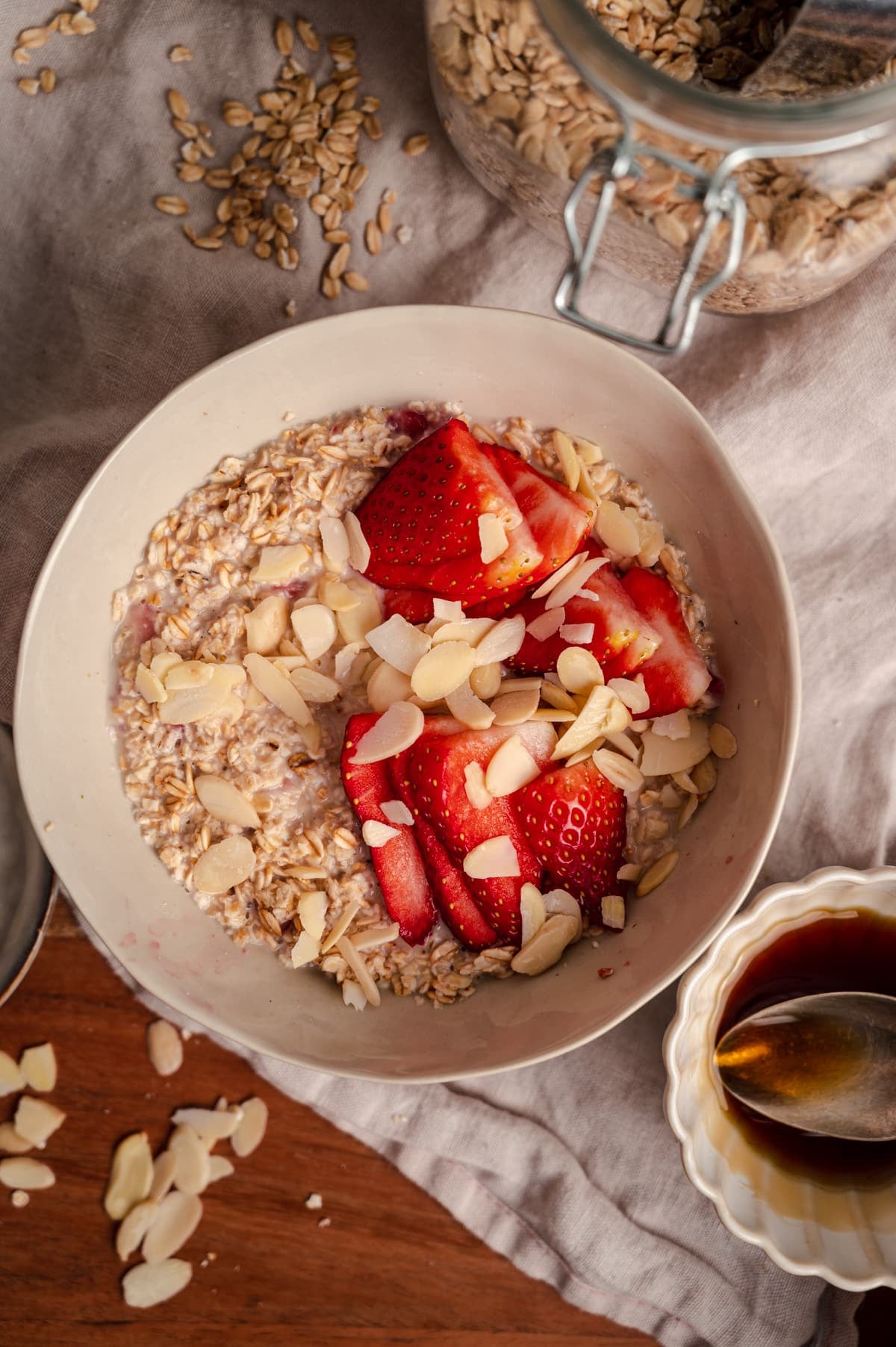 Close up of old-fashioned strawberry oats in a cream bowl with slivered almonds on top.