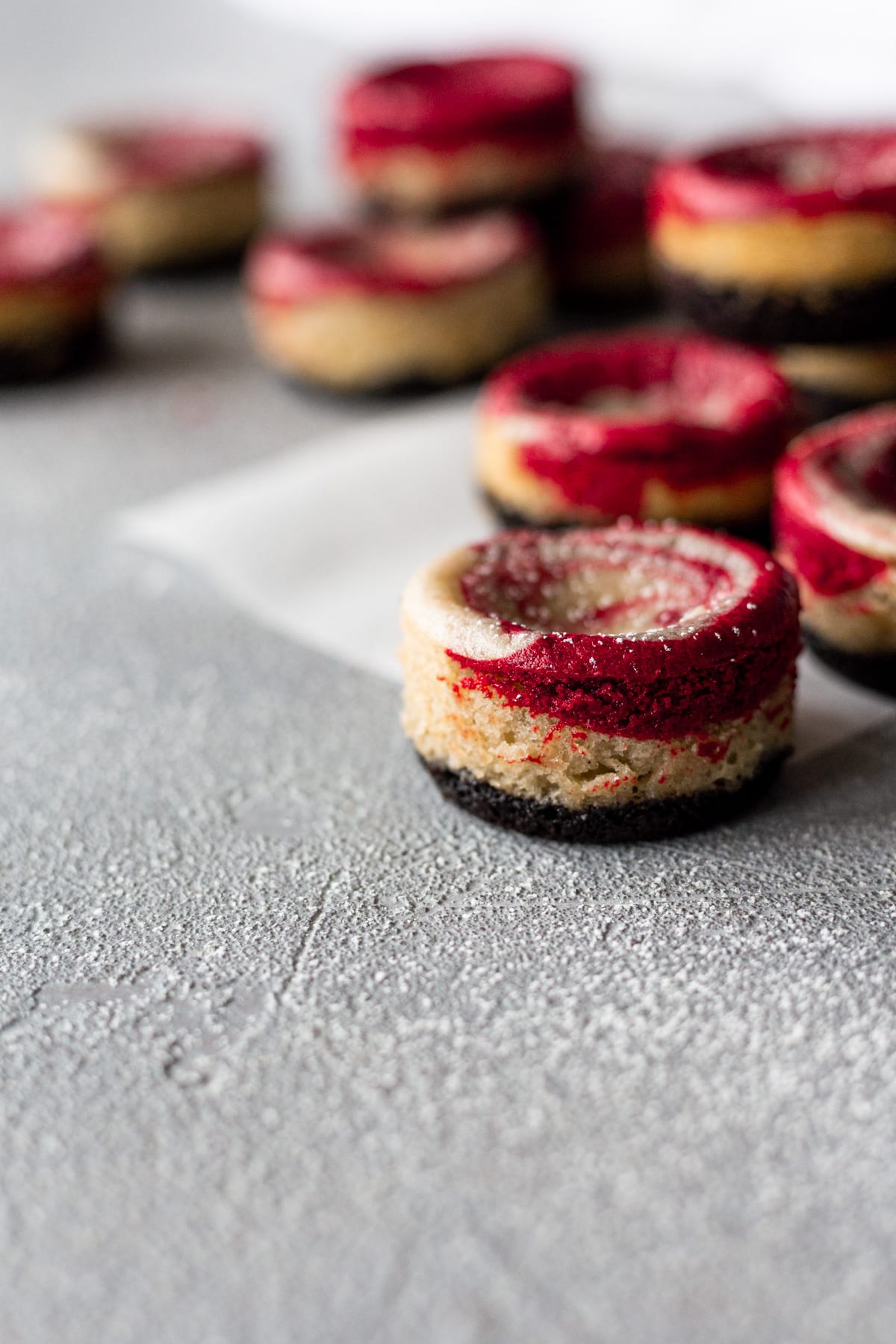 Several red velvet mini vegan cheesecakes on a table.