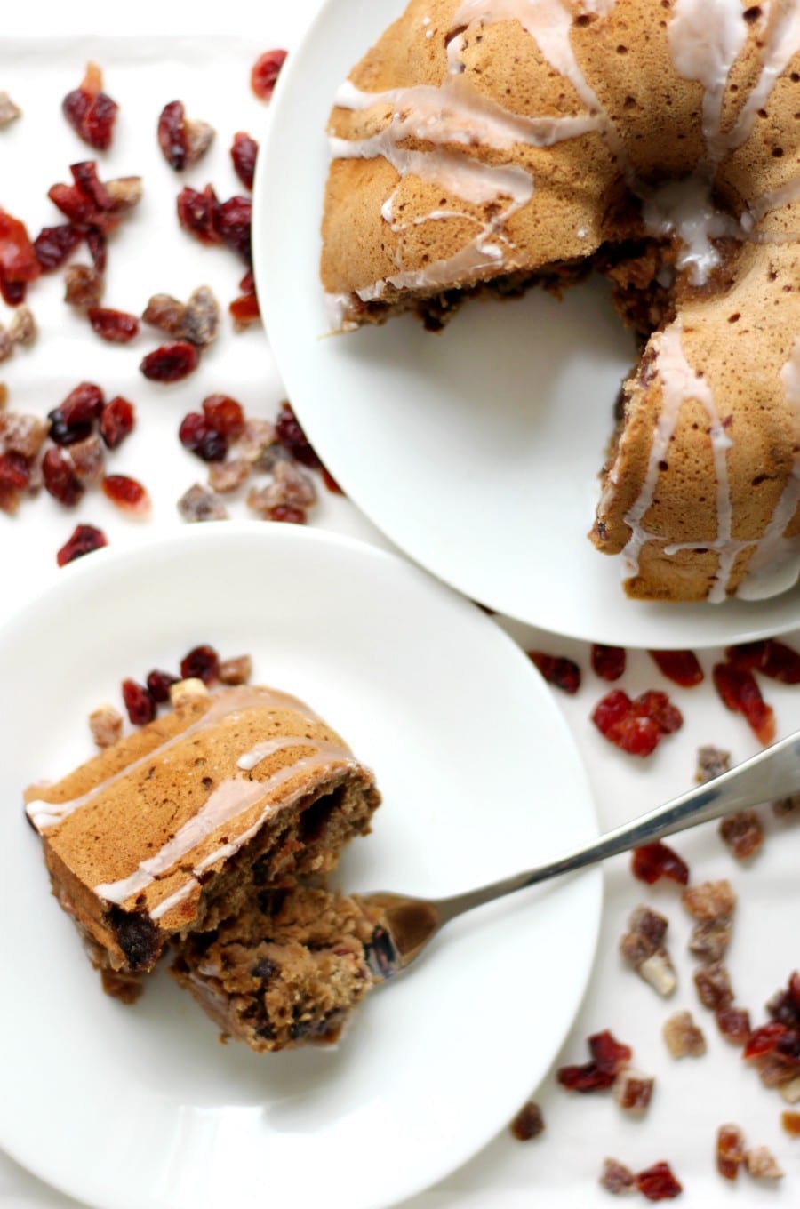 A gluten free vegan fruit cake with a single slice on a white plate.
