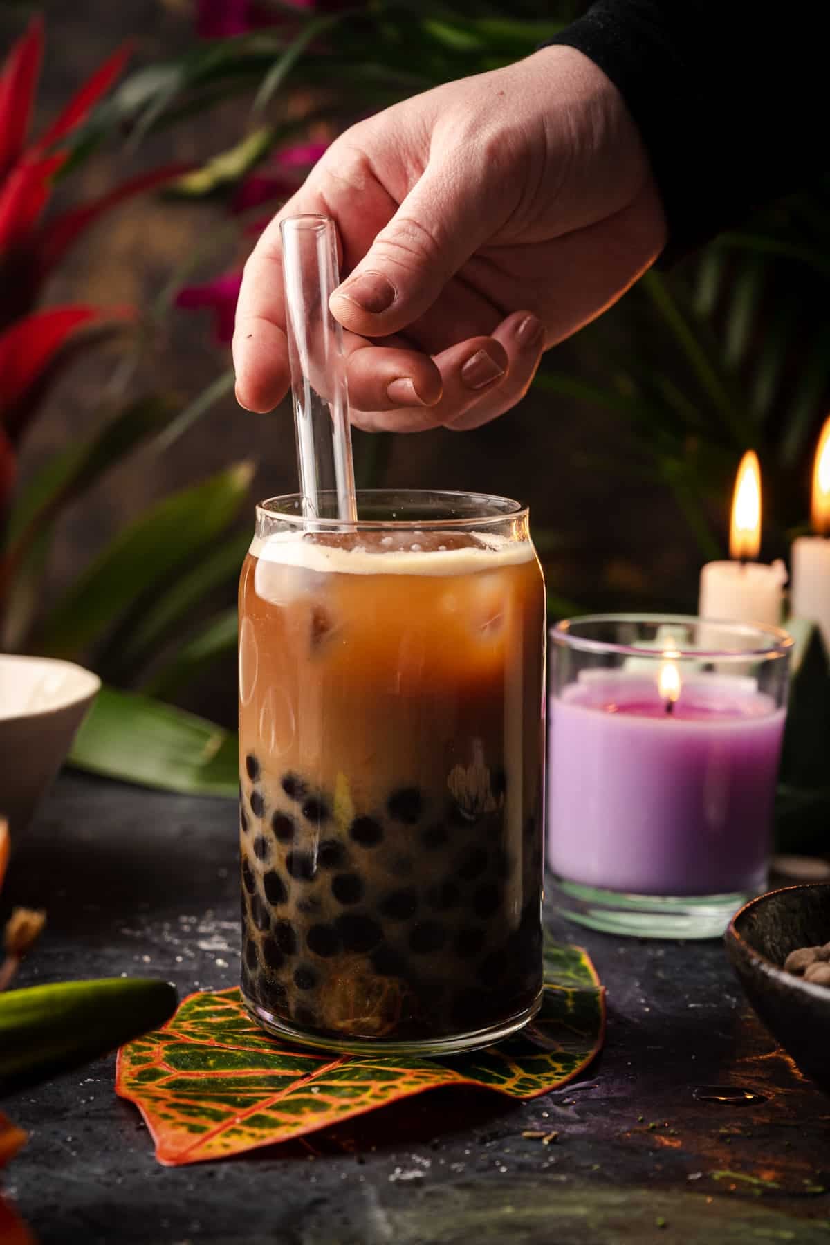 Close up of woman placing a reusable boba straw into a cup of coffee milk tea.