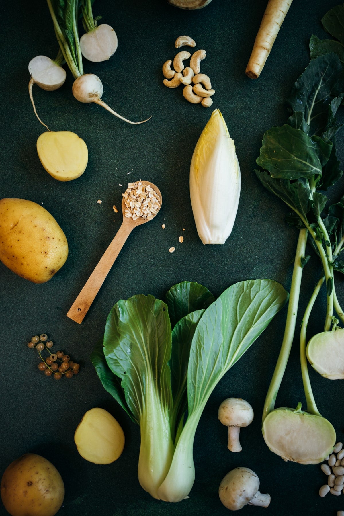 White vegetables, fruits, grain, and seeds, with luscious green leaves.