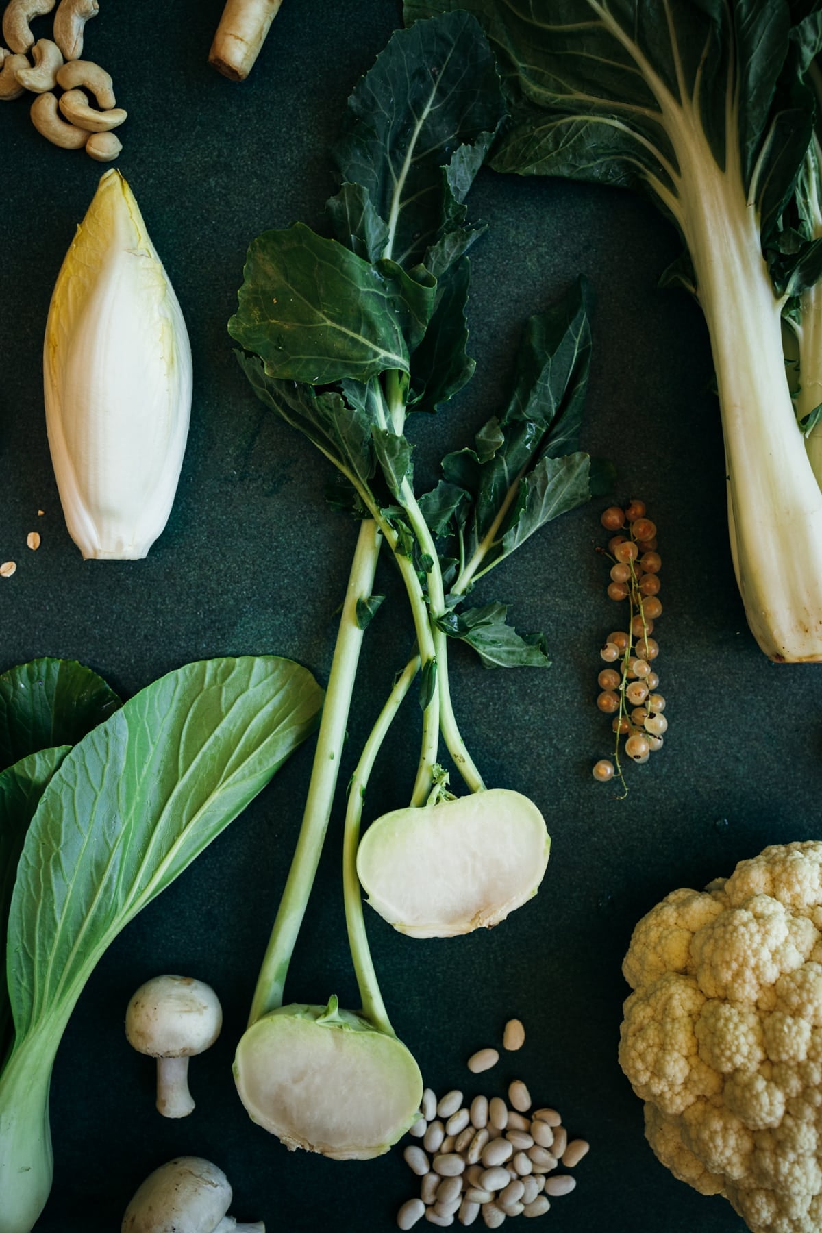 Close up of white foods including kohlrabi sliced in half, oats, endive, and white currant berries.