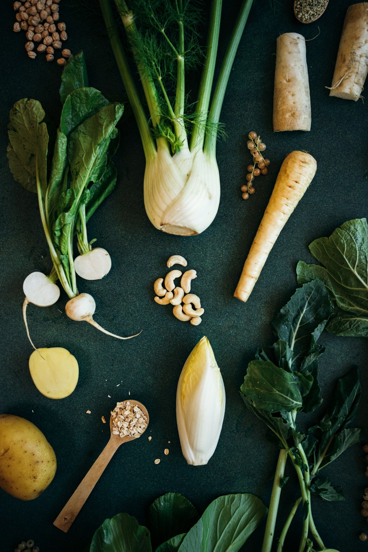 White foods on a green table including white radish, fennel bulb, cashews, oats, and chickpeas.