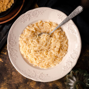 A white plate with orzo in it.