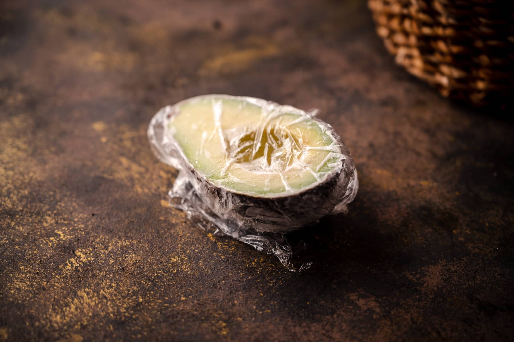 Avocado sliced in half wrapped in plastic wrap.