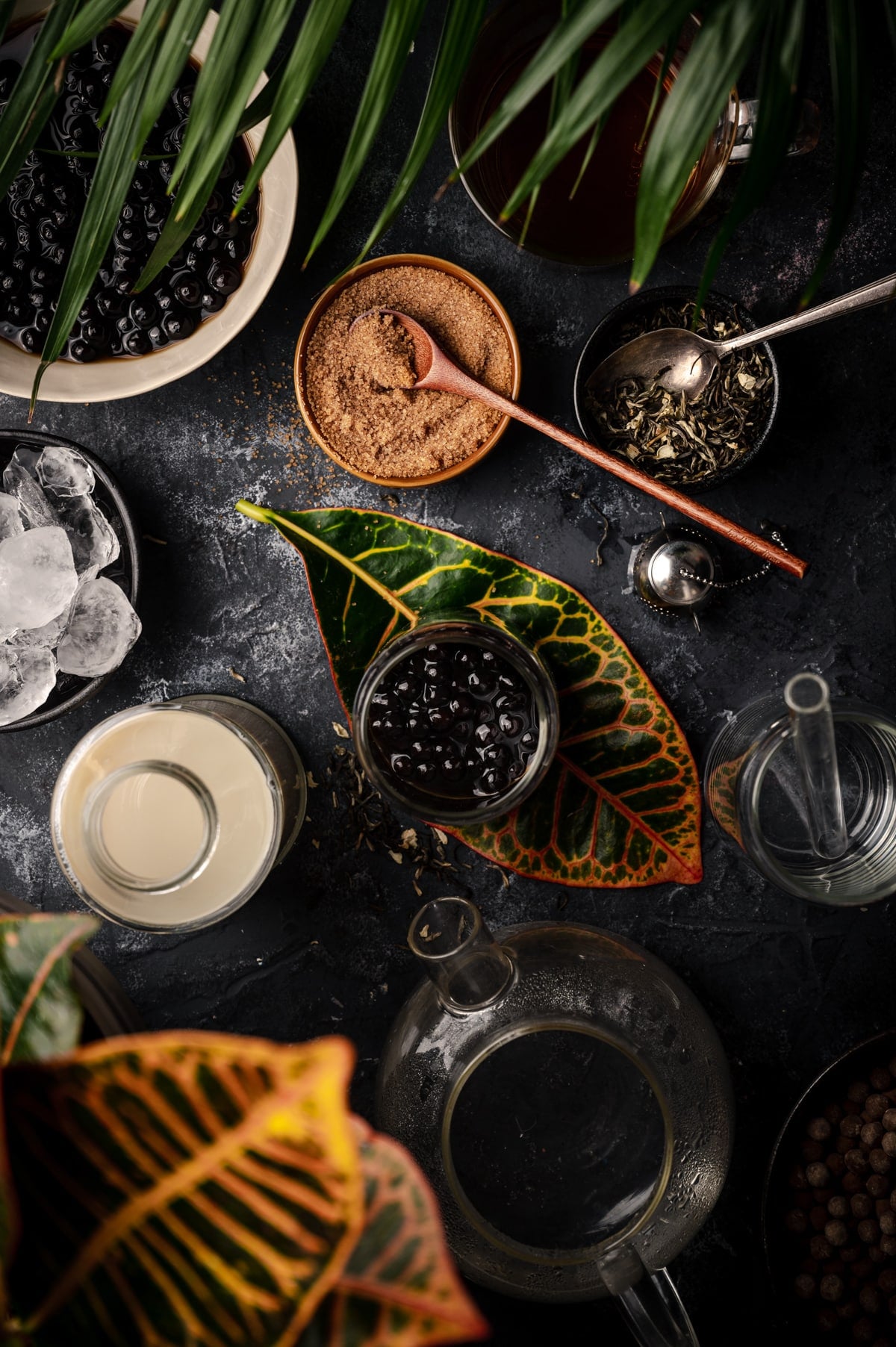 Tapioca boba in a serving glass with ingredients for milk tea surrounding it.