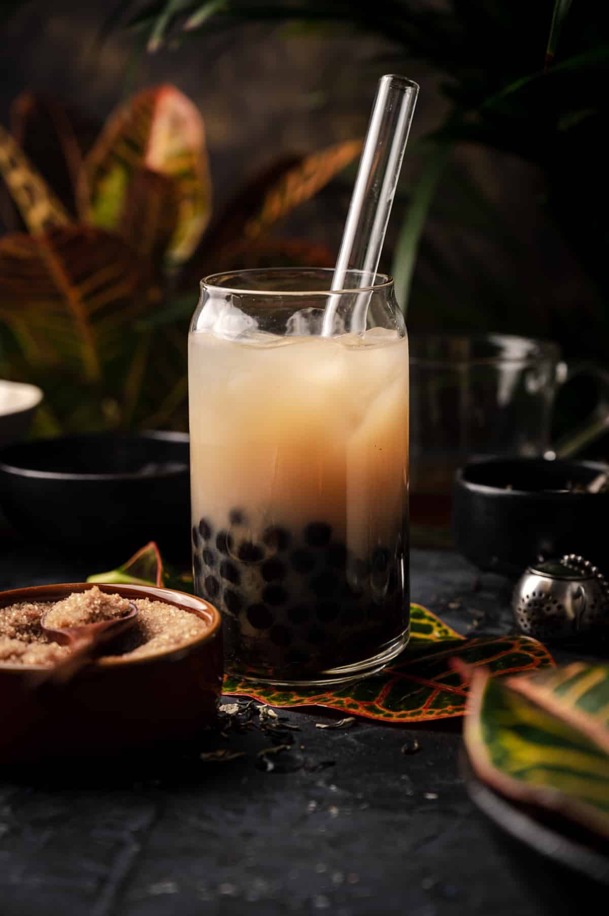 Jasmine milk tea with a lot of boba in the bottom of the glass.