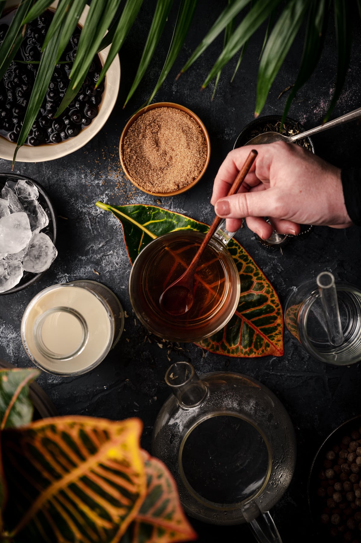 Woman stirring the jasmine tea with a wooden spoon.