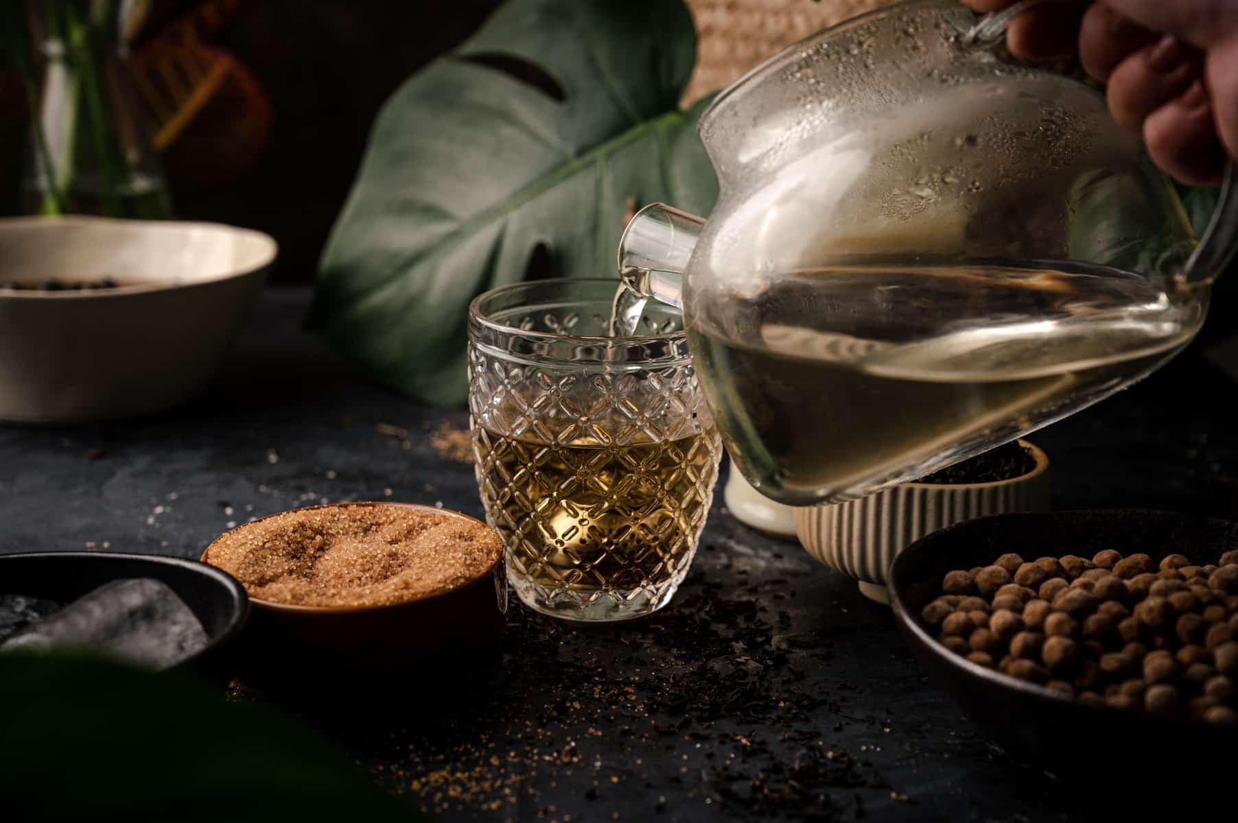 Hot water pouring over oolong tea in a metal tea infuser.
