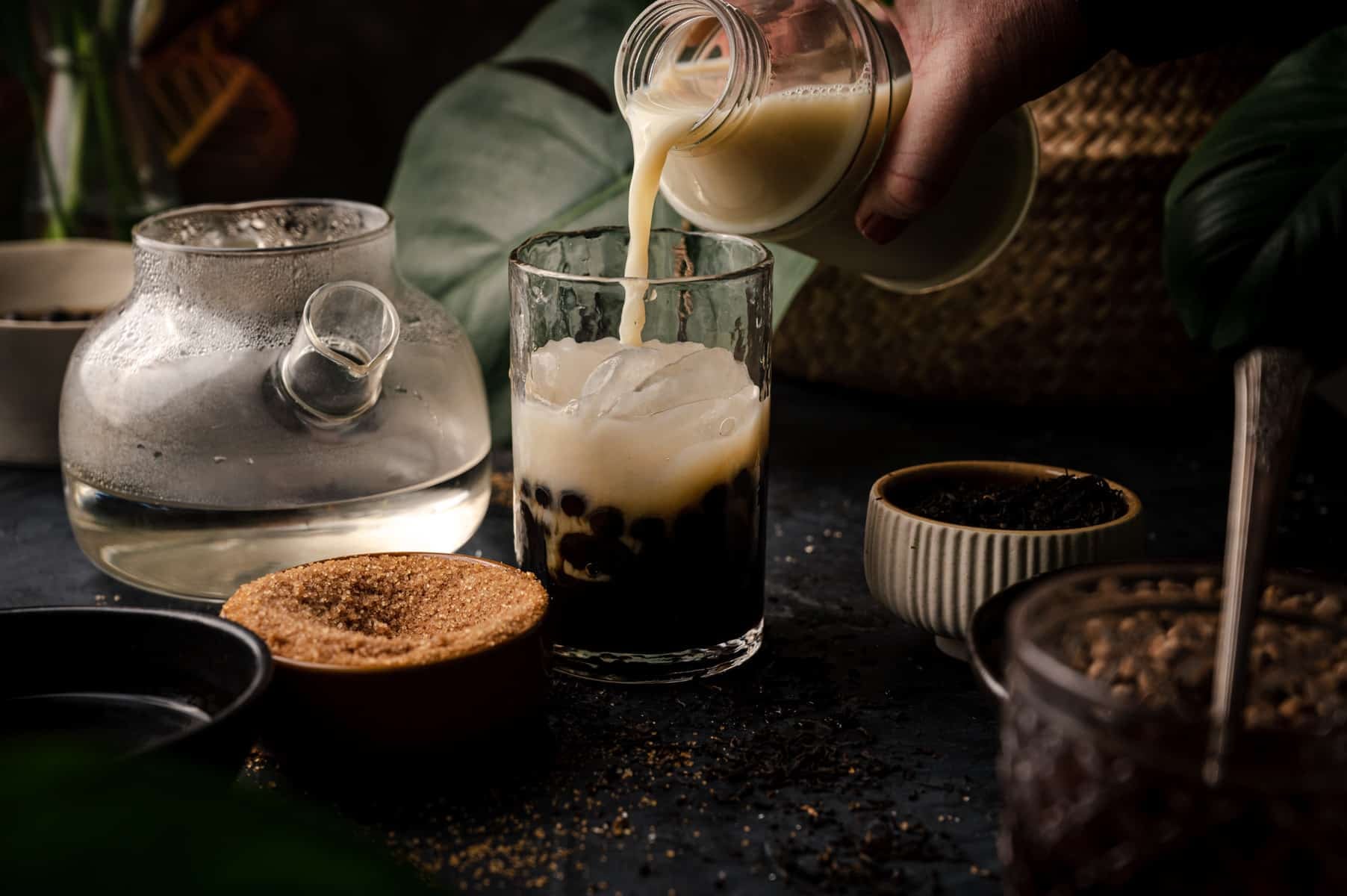 A person pouring milk into a cup of bubble tea.