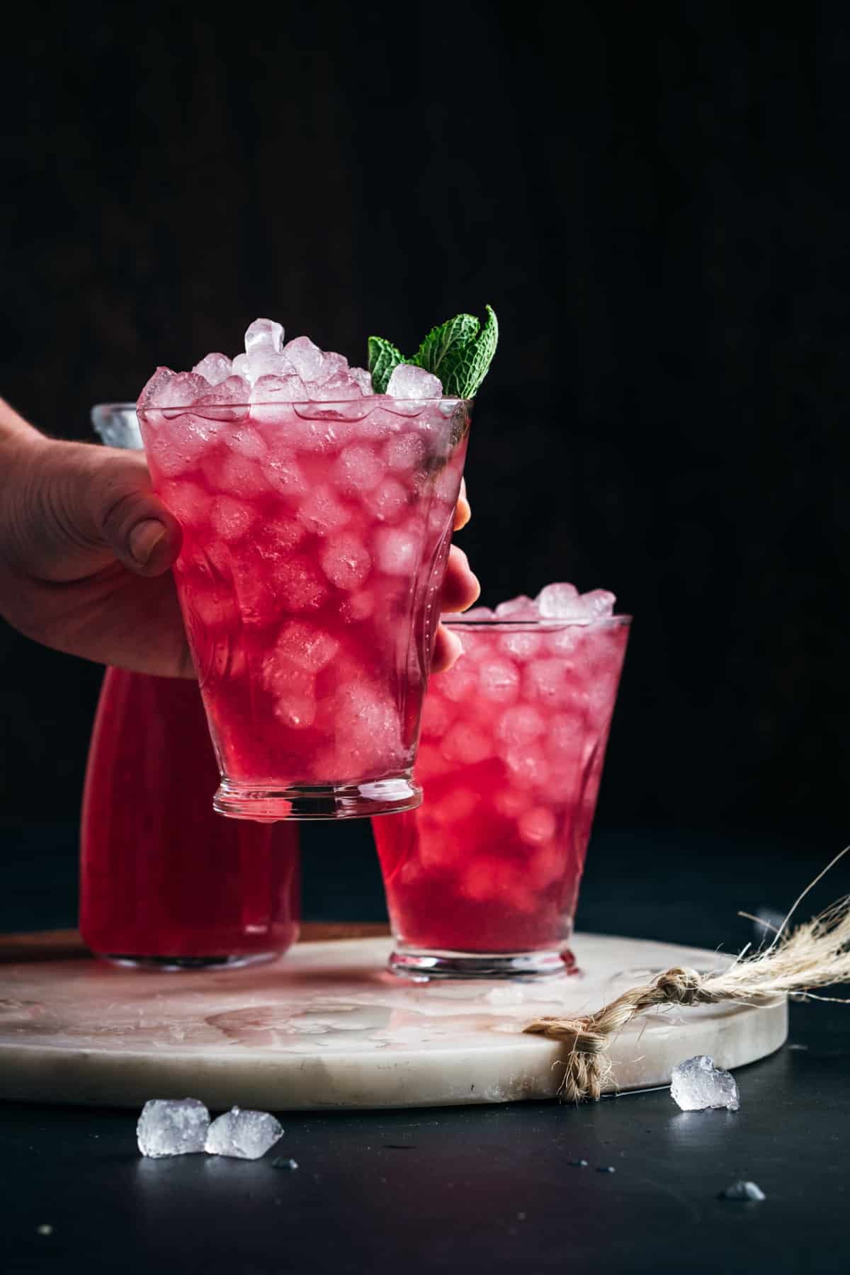 Woman picking up a glass of red colored lemonade.