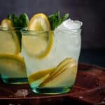 Two glasses of lemonade with ice and mint leaves.