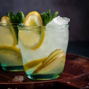 Two glasses of lemonade with ice and mint leaves.