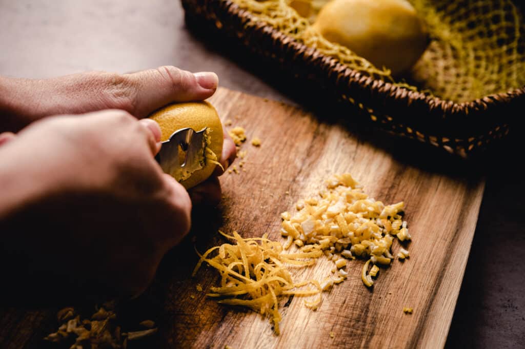 A person slicing a lemon on a cutting board.