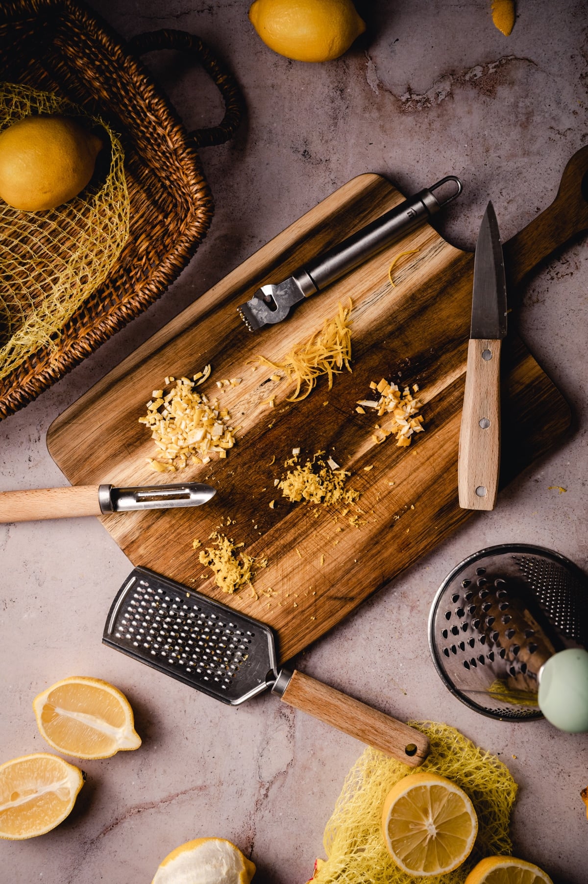 A wooden cutting board with lemons and other kitchen tools.