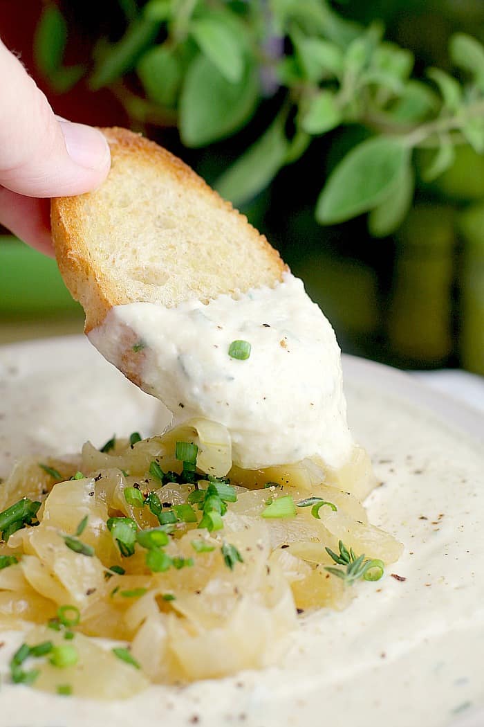A person dipping a croutons into a bowl of soup.