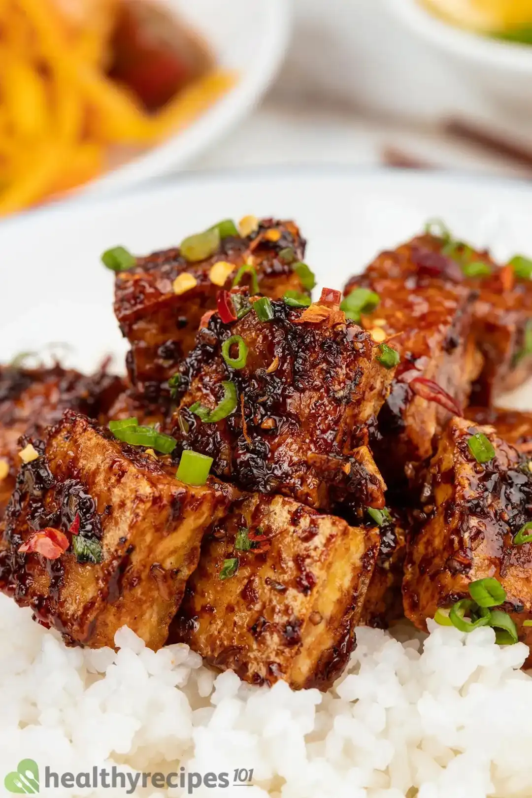Tofu on a plate with rice and sauce.