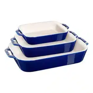 Three nested rectangular ceramic baking dishes with blue exteriors and white interiors, each with handles on the sides, perfect for preparing a hearty vegan casserole.
